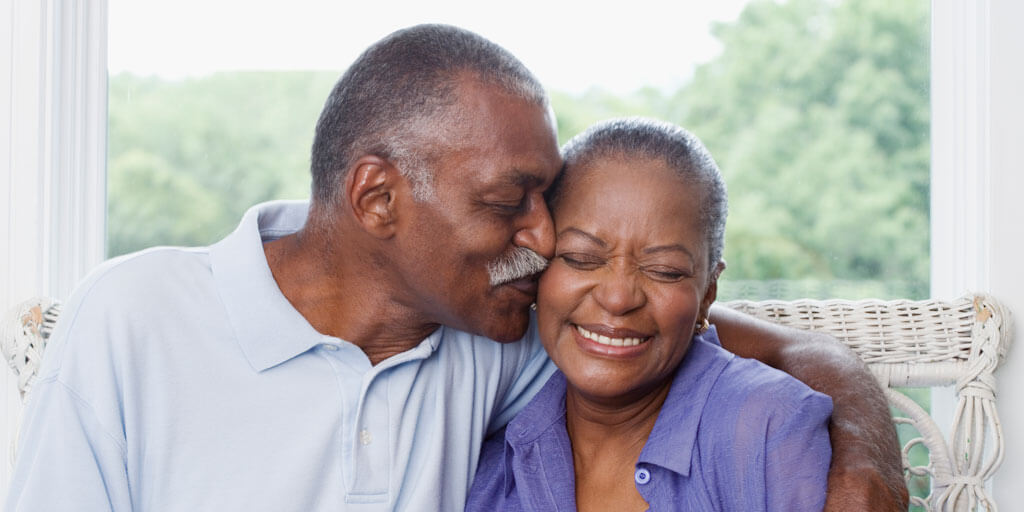 50+ African-American couple hugging and smiling.